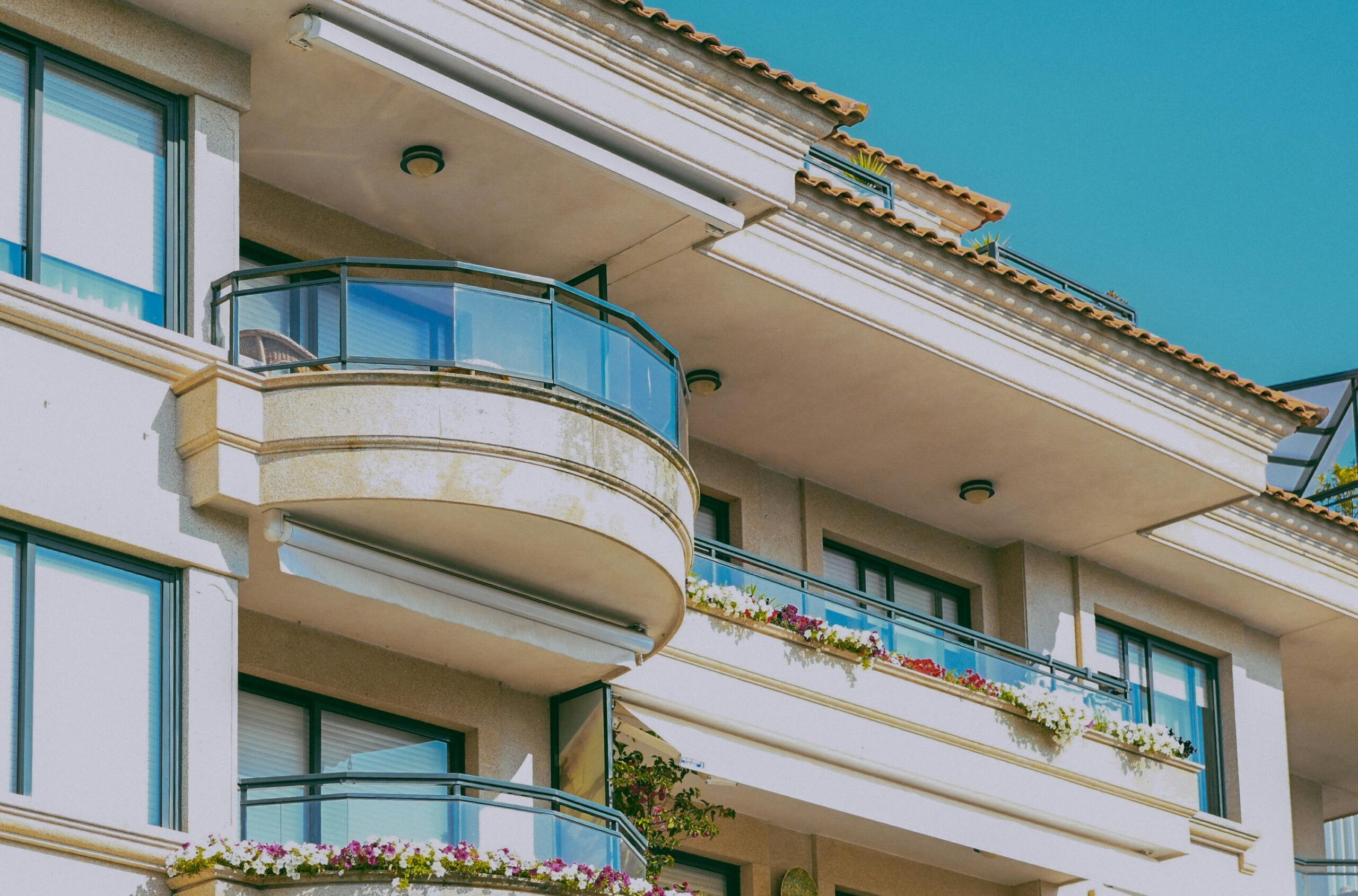 Stylish architecture featuring glass balconies and flower decorations on a sunny day.